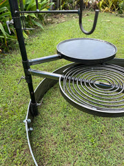 Outdoor cooking setup with a flat top grill and coil burner on a grassy area.
