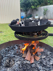 Outdoor cooking setup with a black frying pan over a fire pit.