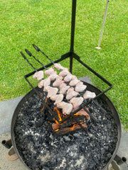Fire pit with hot coals and a metal grate on a grassy background