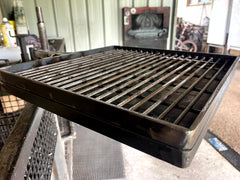 Black metal grill grate on a stand with a workshop background