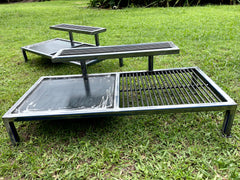 Metal outdoor grill and benches on grass