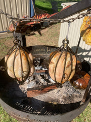 Meat hanging over a fire pit on a chain